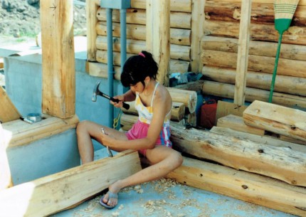 Jenn, 13, chiseling out holes for the electrical boxes in the logs for the house.